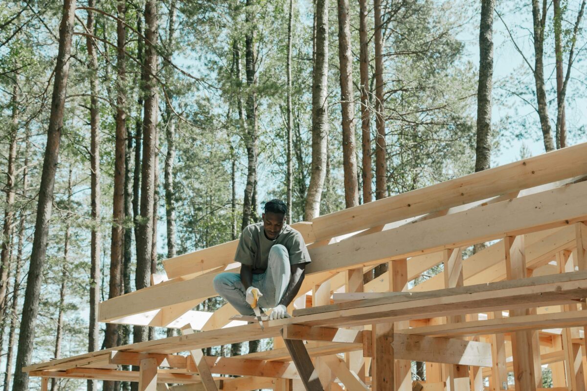 Un homme en pleine construction d'une charpente en bois, symbolisant la construction de solides fondations grâce à ses valeurs.