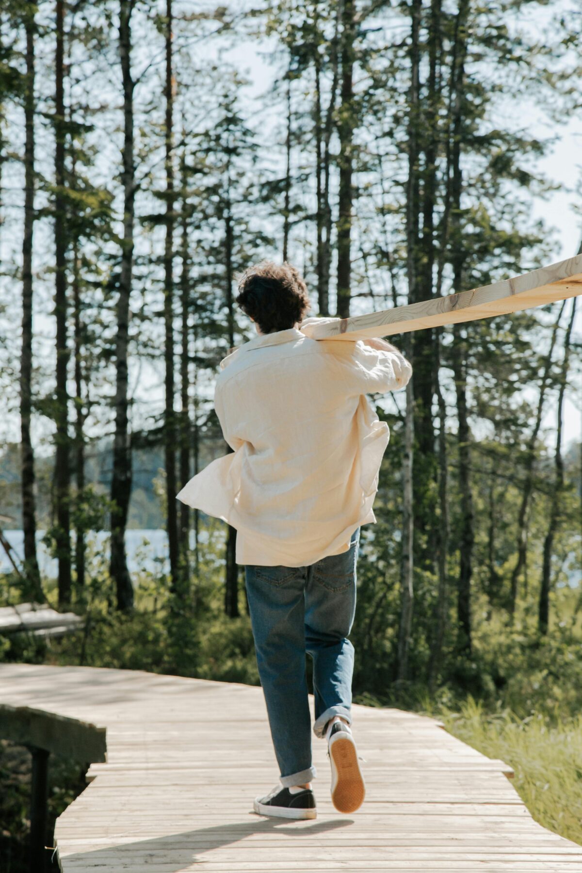 Une personne portant une planche de bois, marchant en pleine nature, illustrant la réévaluation et l'évolution de ses valeurs personnelles au fil du temps.