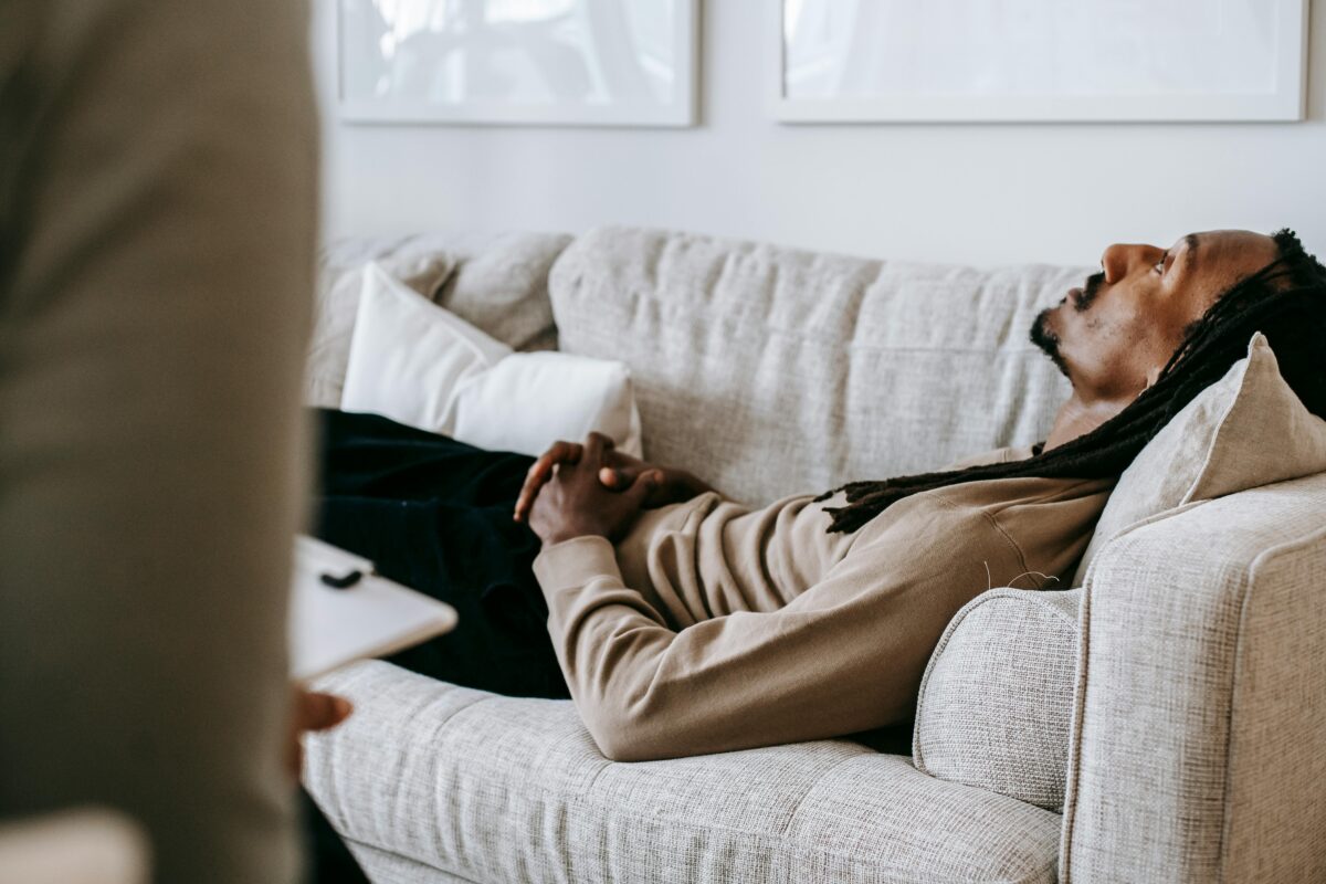 Séance de psychanalyse : un patient allongé sur un canapé, les mains croisées, pendant que le thérapeute l'écoute attentivement.