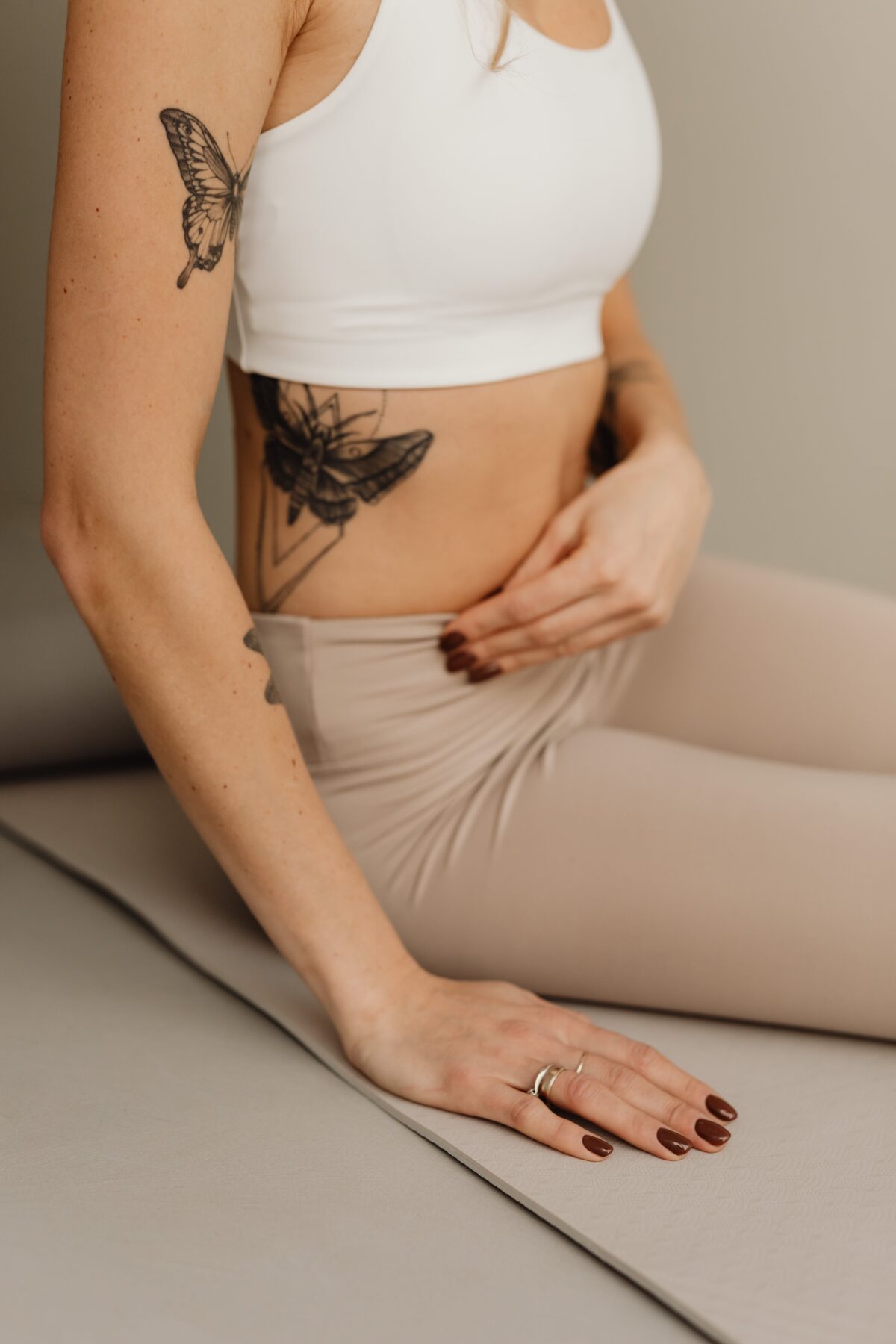 Une femme assise en tenue de yoga, posant la main sur son ventre, symbolisant l'écoute de soi et le ressenti de ses émotions.