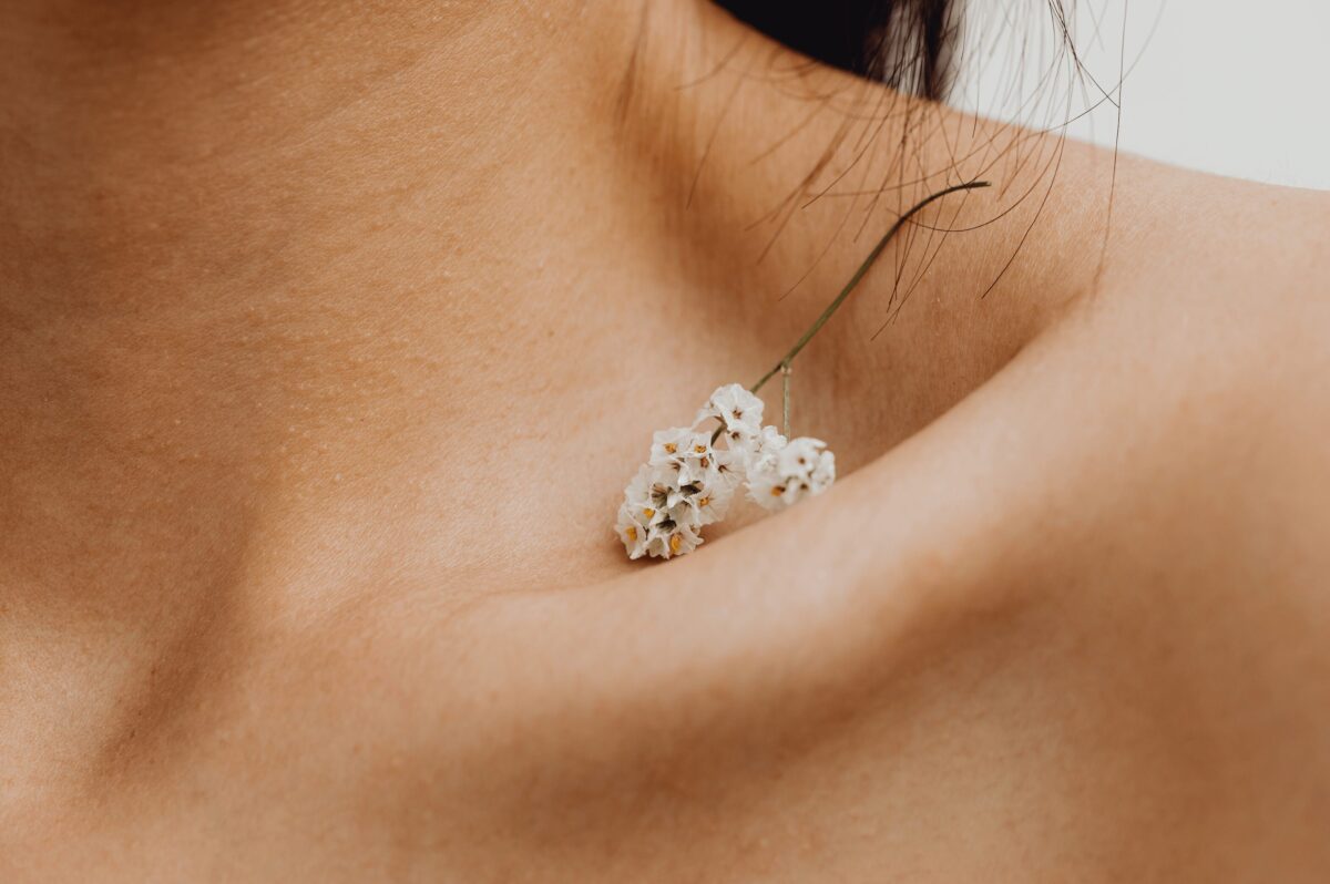 Écouter son corps avec bienveillance : image symbolique illustrant la douceur et le soin porté au corps, avec une fleur délicate posée sur une épaule.