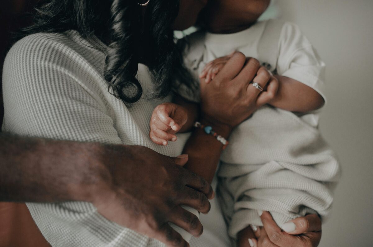 Un moment de tendresse entre des parents et leur enfant, illustrant un attachement sécure basé sur la confiance, l'amour et la sécurité émotionnelle.