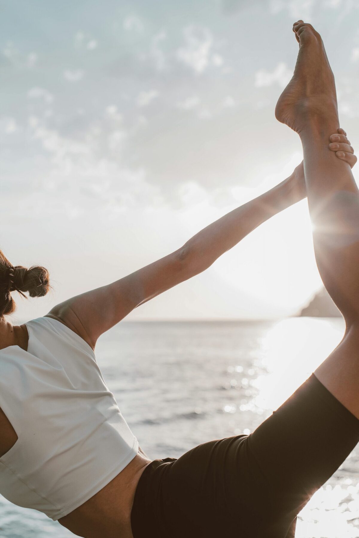 Femme pratiquant le yoga au bord de l’océan, illustrant la flexibilité mentale, un élément clé pour sortir d'une dépression et retrouver un équilibre intérieur.