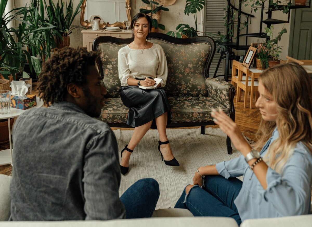 Un couple en thérapie avec une psychologue dans un cadre chaleureux. 